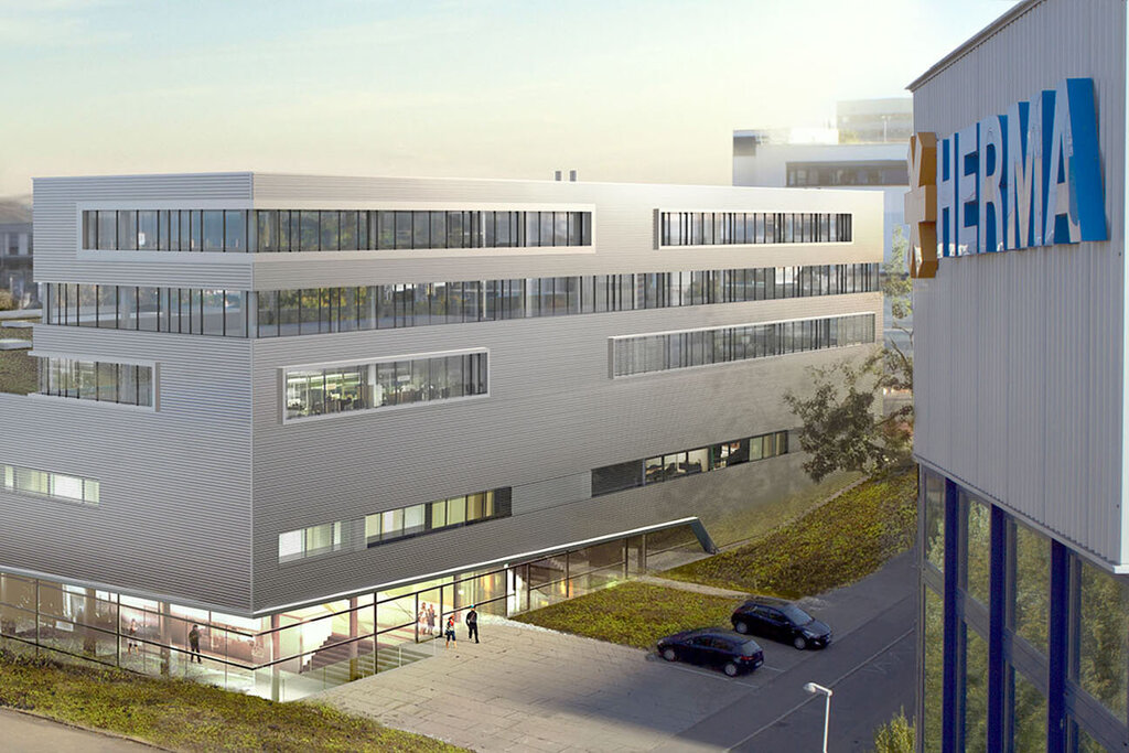 Moderne kantoorgebouwen met een plat dak en grote ramen, omringd door groen en een parkeerplaats.